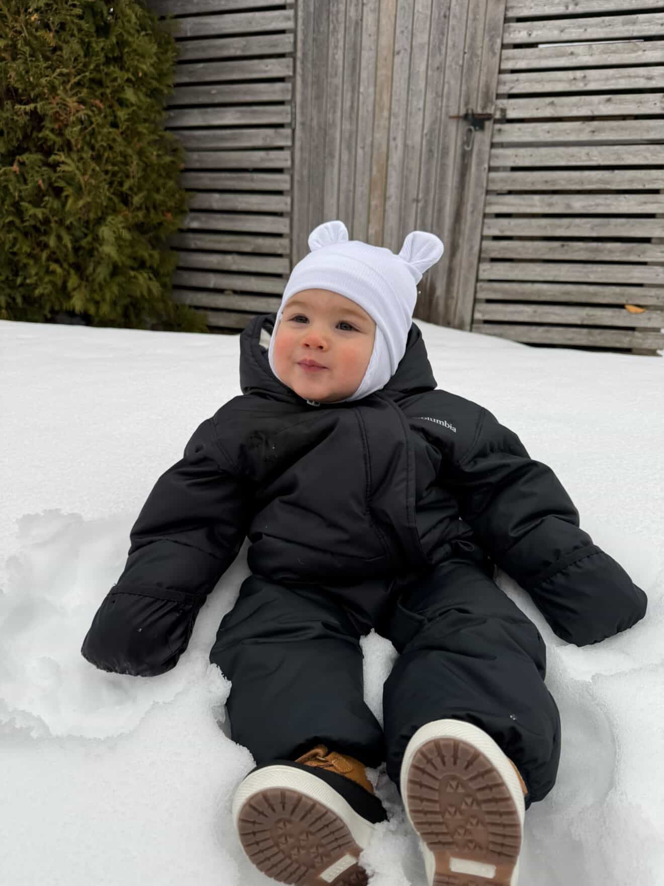 Bébé portant une tuque blanche Kplla avec oreilles ourson dans la neige en hiver